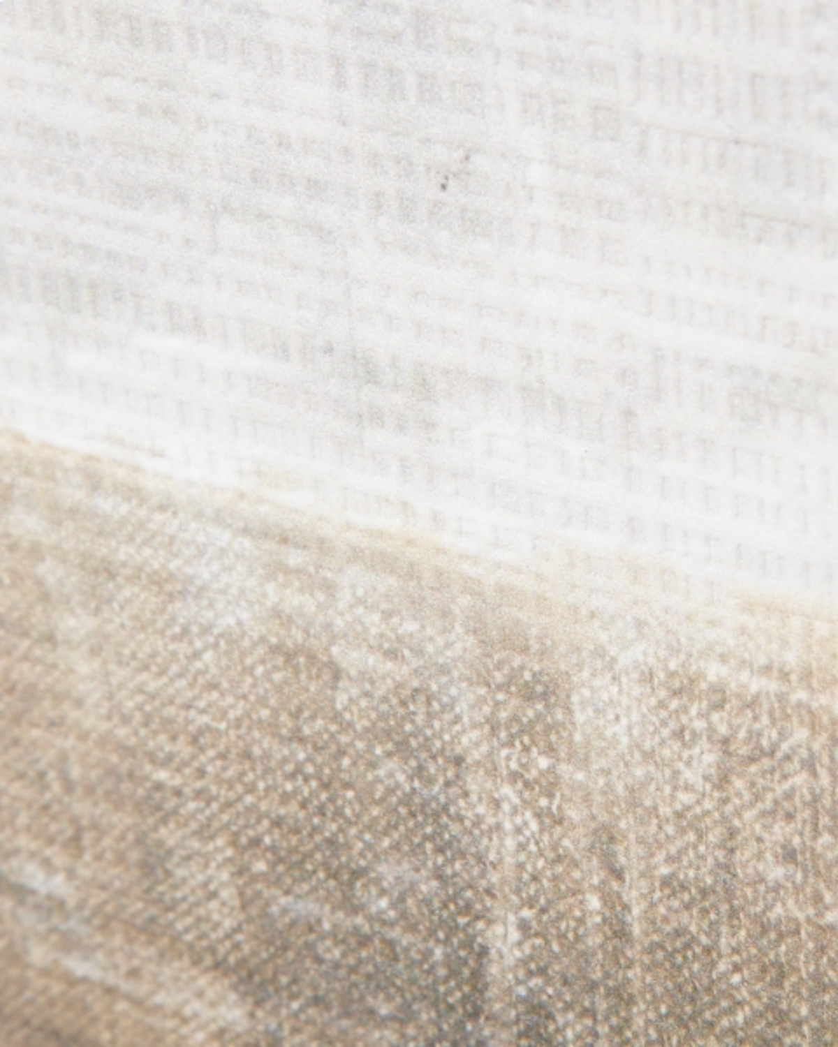 Close-up of a textured fabric with a horizontal color-blocked pattern, featuring a white top section and a warm beige bottom section.